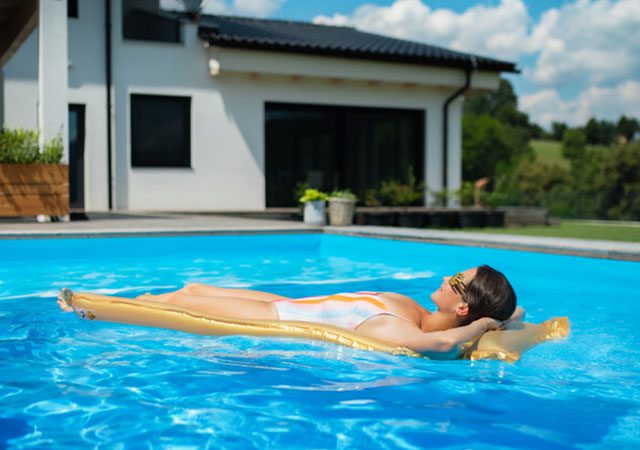 Woman laying on pool float in backyard pool